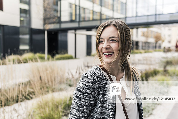 Lächelnde junge Frau vor dem Bürogebäude