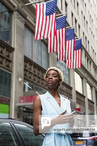 USA  New York  junge blonde Afroamerikanerin mit Smartphone