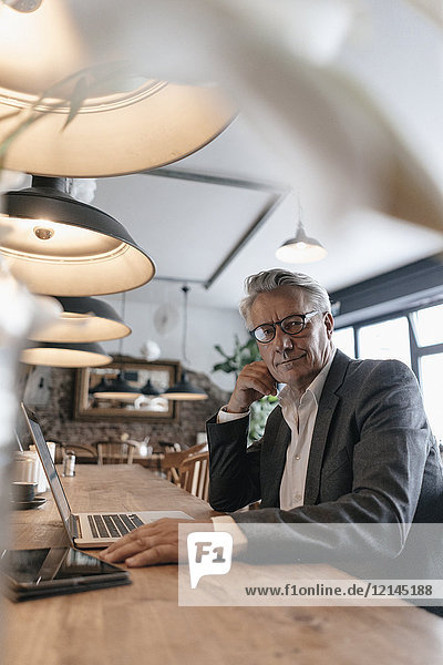 Senior Geschäftsmann sitzt im Cafe und arbeitet am Laptop