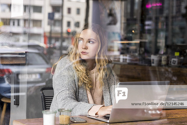 Portrait of young woman working on laptop in a coffee shop