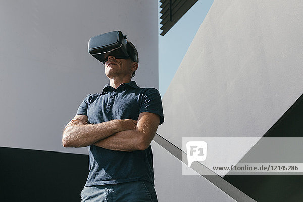 Erwachsener Mann mit VR-Brille zwischen Wänden moderner Architektur