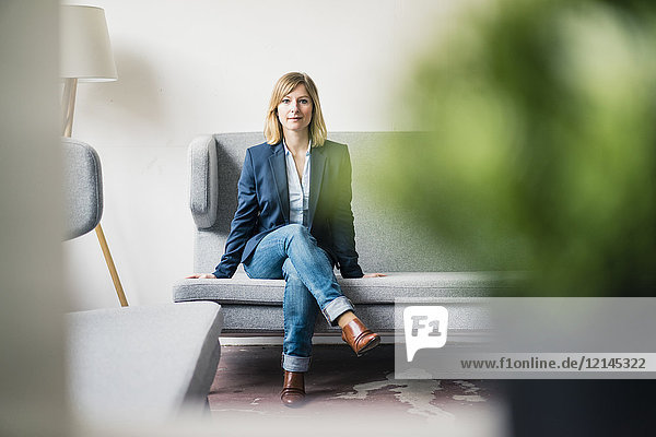 Businesswoman sitting on couch in office lounge