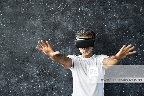 Mature man wearing VR glasses reaching out with hands