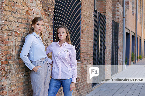 Zwei seriöse Geschäftsfrauen vor dem Backsteingebäude