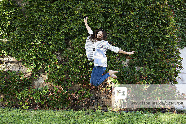 Happy young woman jumping in the air outdoors