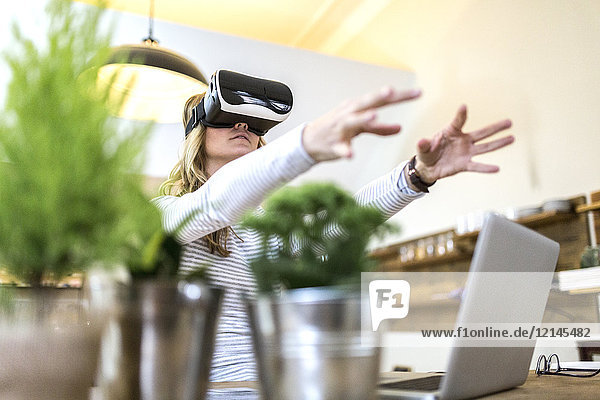 Woman with VR glasses and laptop at home