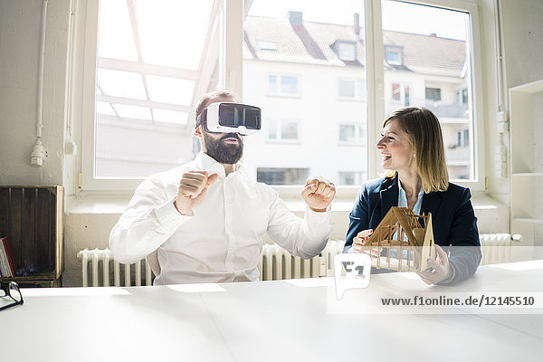 Woman and man with house model and VR glasses in office