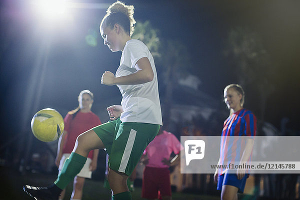 Junge Fußballspielerin, die nachts auf dem Spielfeld trainiert.