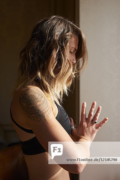 Gelassene Frau mit Tattoo-Meditation mit Händen in der Mitte des Herzens  anjali mudra