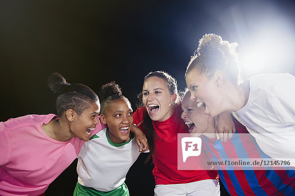 Enthusiastic young female soccer teammates celebrating  cheering in huddle