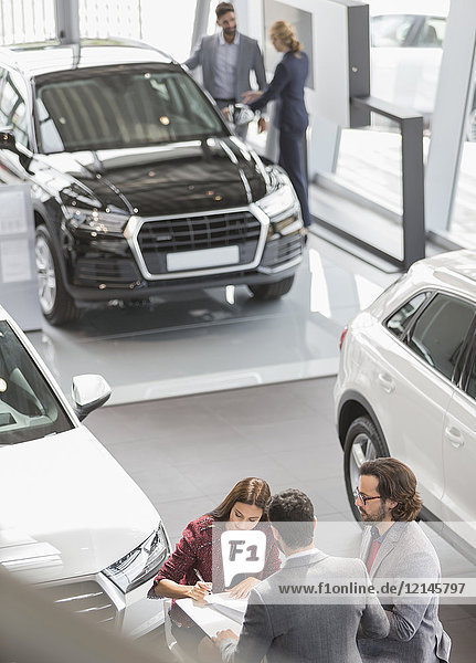 Autoverkäufer und Kunden im Autohaus Showroom