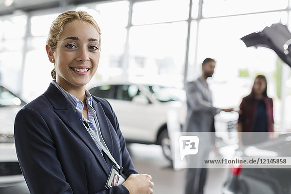 Portrait lächelnde  selbstbewusste Autoverkäuferin im Autohaus-Showroom