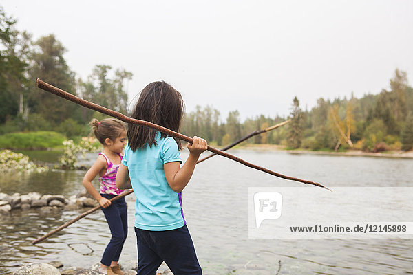 Girls fishing with sticks at lake