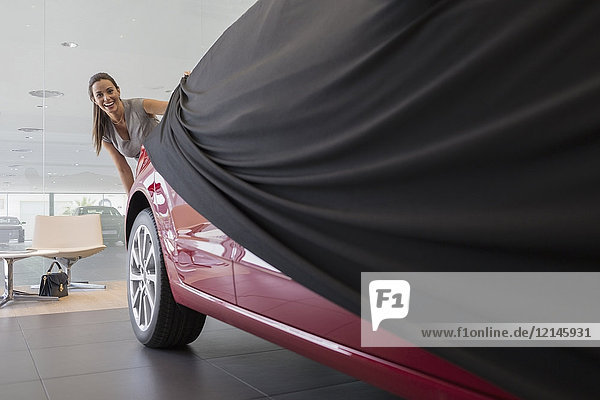 Kundin beim Abnehmen des Deckels vom Neuwagen im Autohaus