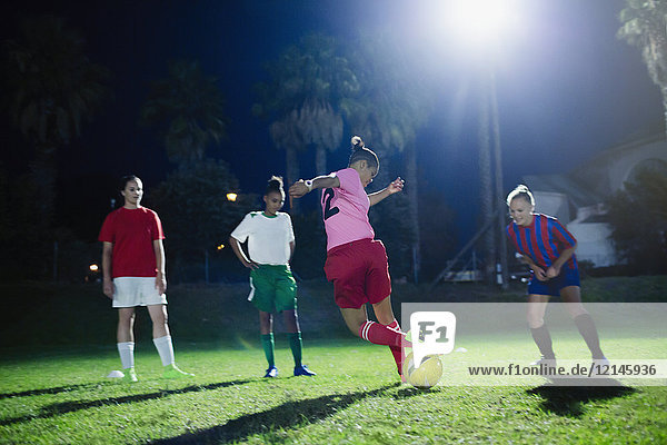 Young female soccer players practicing on field at night