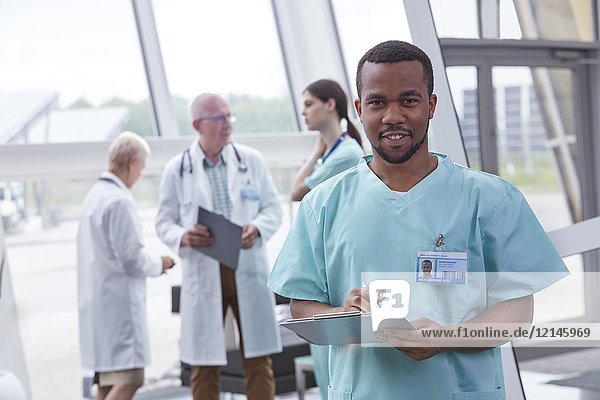 Porträt eines selbstbewussten Krankenpflegers mit Zwischenablage in der Lobby des Krankenhauses