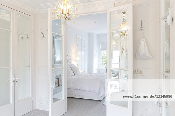 Weißes  luxuriöses Wohnschlafzimmer mit Fenstertüren und Kronleuchter