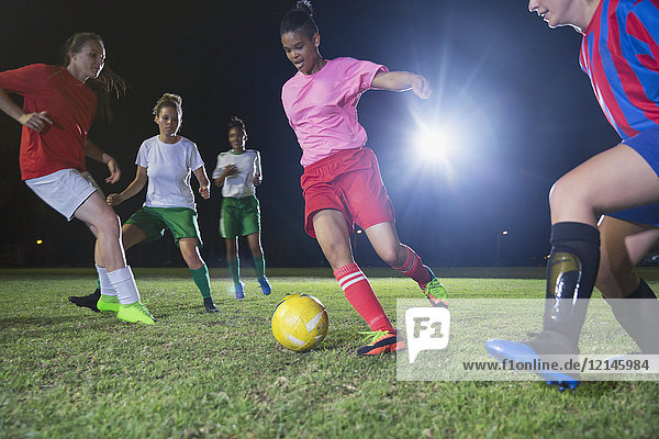 Junge Fußballspielerinnen spielen nachts Fußball auf dem Spielfeld