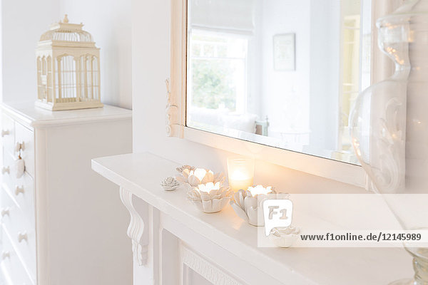 Ruhige Kerzen in Blumenkerzenhaltern auf weißem Mantel