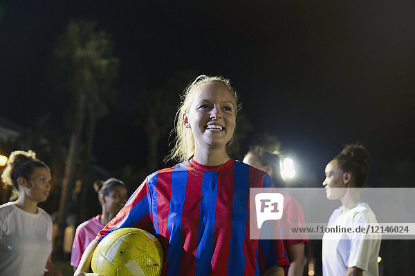 Portrait lächelnde  selbstbewusste junge Fußballspielerin mit Ball
