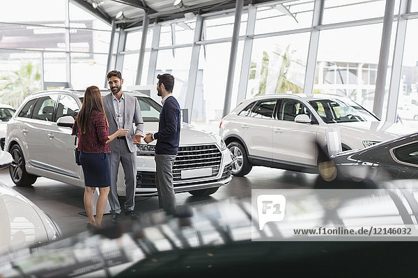 Autoverkäufer im Gespräch mit Kunden im Autohaus-Showroom