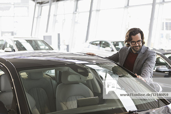 Männlicher Kunde, der ein neues Auto im Autohaus in Augenschein nimmt