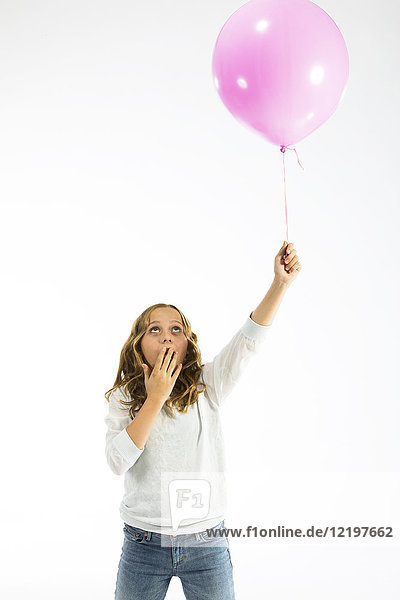 Mädchen spielt mit rosa Luftballon  handbedeckter Mund