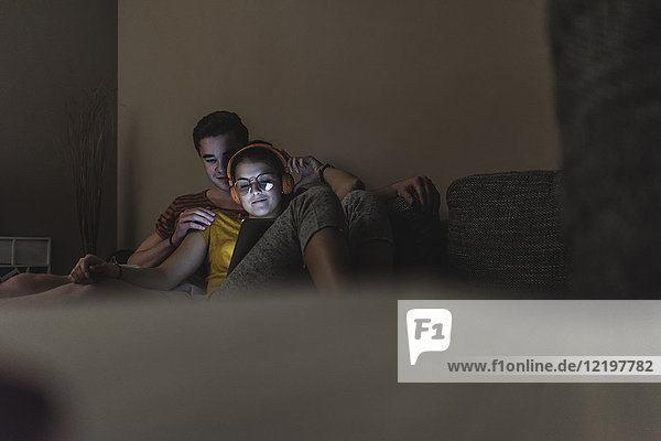 Paar mit Kopfhörer und Tablett zum Entspannen auf der Couch zu Hause
