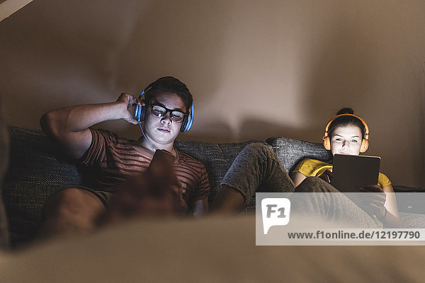 Paar mit Kopfhörer zum Entspannen auf der Couch zu Hause