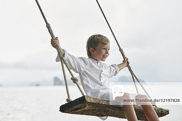 Thailand  Ko Yao Noi  glücklicher Junge auf einer Schaukel am Strand