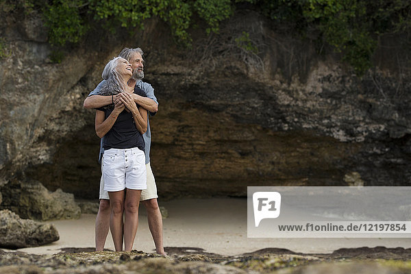 Affectionate senior couple hugging at beach