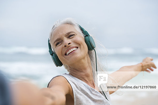 Portrait of beautiful smiling senior woman dancing on beach