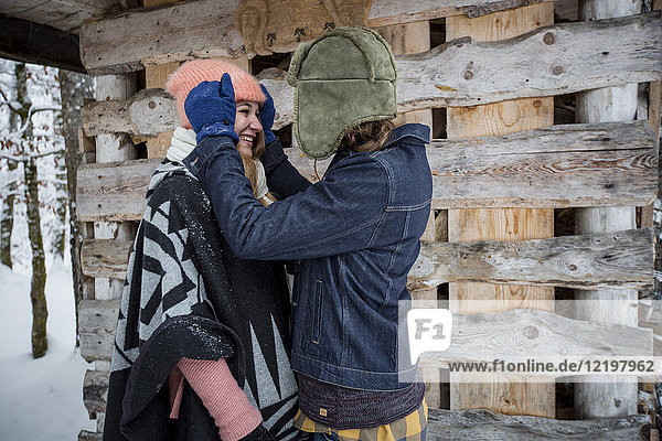 Glückliches Paar vor dem Holzhaufen im Freien im Winter