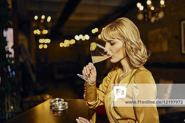 Elegante Frau trinkt Cocktail in einer Bar