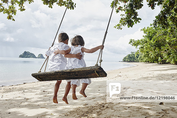 Thailand  Ko Yao Noi  Junge und kleines Mädchen auf einer Schaukel am Strand