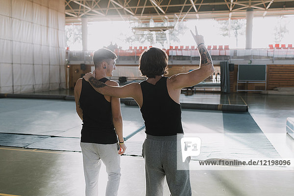 Rear view of two happy gymnasts standing in gym