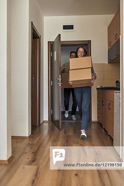 Young women and man carrying cardboard boxes into a room