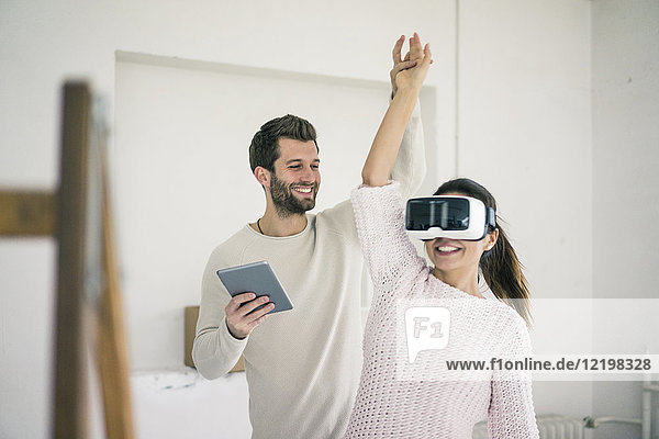 Mann hebt Frauenarm mit VR-Brille in neuem Zuhause