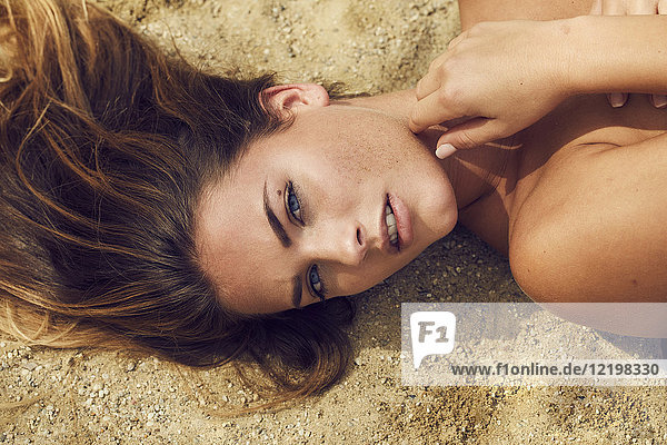 Portrait of lascivious young woman lying on the beach
