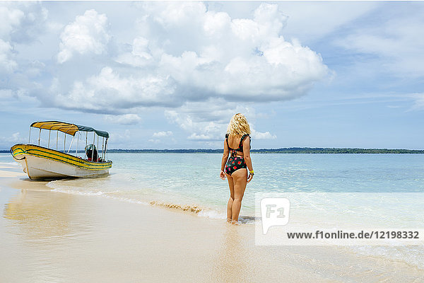 Panama  Bocas del Toro  Cayo Zapatilla  Frau von hinten am Strand mit festgemachtem Boot