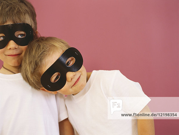 Porträt von zwei lächelnden kleinen Jungen mit schwarzen Augenmasken