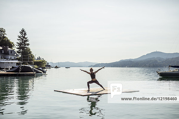 Frau beim Yoga auf dem Floß im See