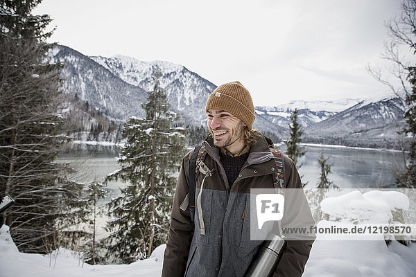 Glücklicher Mann in alpiner Winterlandschaft mit See