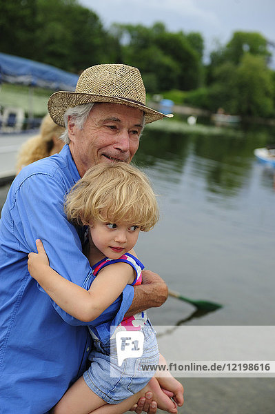 Little girl on arms of her grandfather at lakeshore