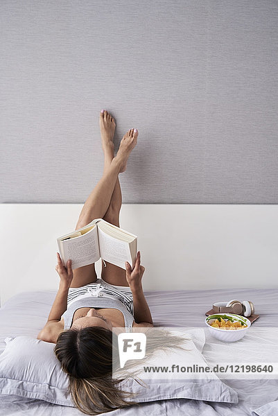 Entspannte Frau beim Lesen eines Buches im Bett