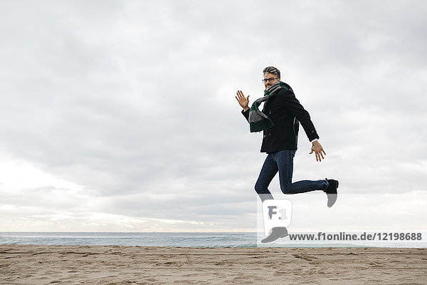 Mann beim Springen am Strand im Winter