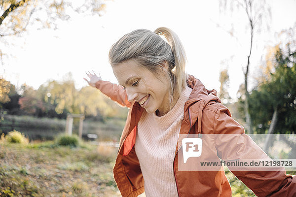 Porträt einer glücklichen jungen Frau  die im herbstlichen Park balanciert.