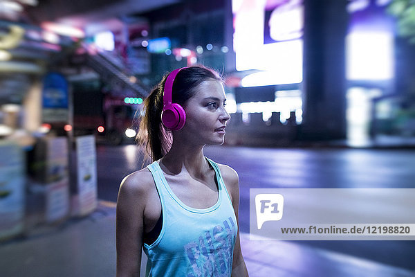 Young woman in pink sportshirt in modern urban setting at night