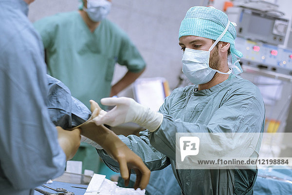 Assistentin beim Anziehen des Handschuhs vor einer Operation