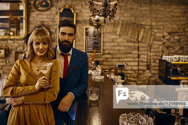 Portrait of elegant couple with drinks in a bar